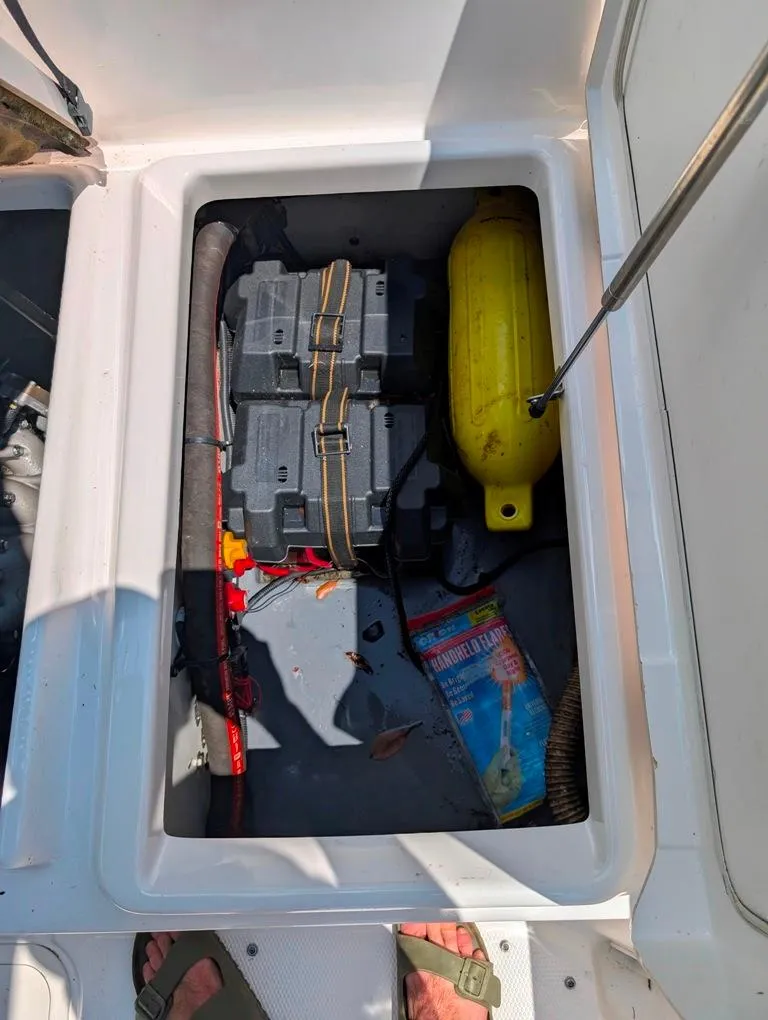 Slide: The Image of Storage compartment of 2021 Yamaha Boats 195 FSH Sport with battery and safety equipment. - 13
