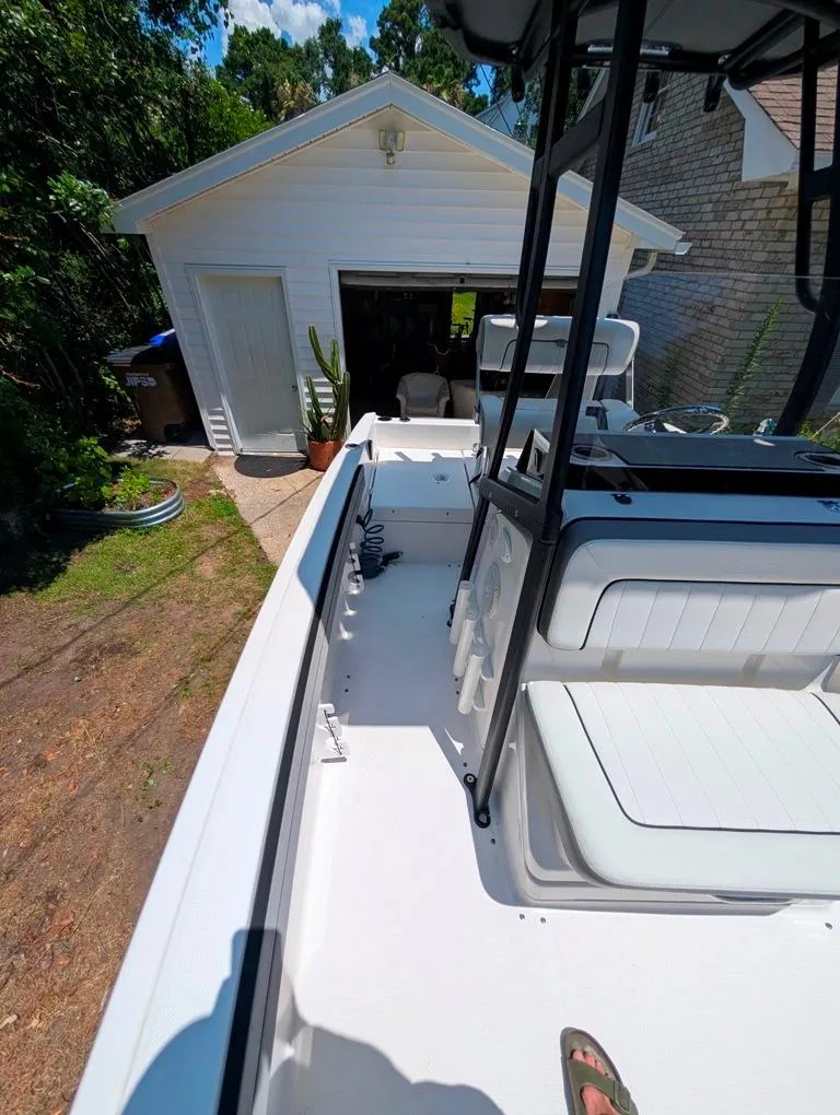 Slide: The Image of 2021 Yamaha Boats 195 FSH Sport parked near a garage, surrounded by greenery. - 27