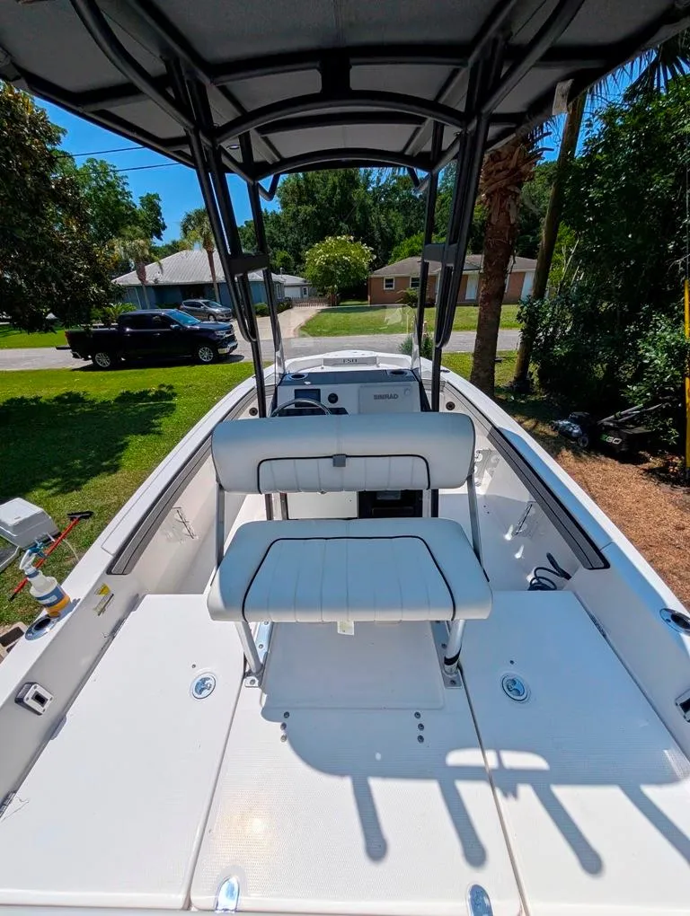 Slide: The Image of 2021 Yamaha Boats 195 FSH Sport interior with seating and console, parked in a residential area. - 30