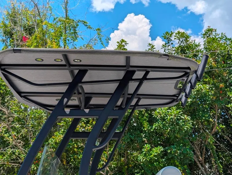 Slide: The Image of 2021 Yamaha Boats 195 FSH Sport T-top against a blue sky and lush greenery. - 33