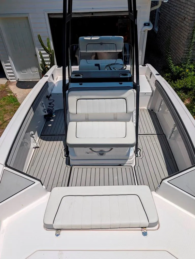 Slide: The Image of 2021 Yamaha Boats 195 FSH Sport interior with seating and console, docked near a house. - 47