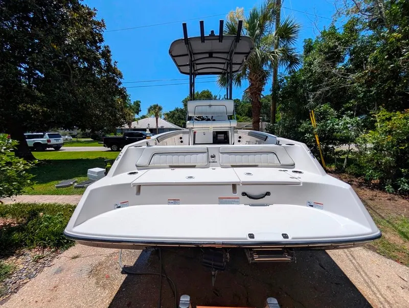 Slide: The Image of 2021 Yamaha Boats 195 FSH Sport, rear view, parked outdoors, surrounded by trees. - 5