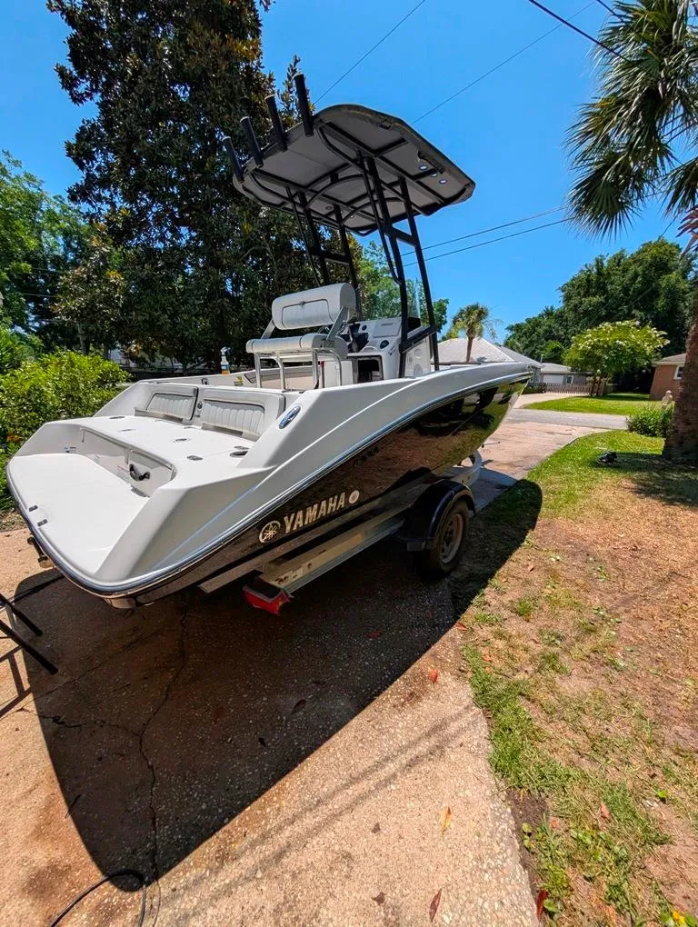Slide: The Image of 2021 Yamaha Boats 195 FSH Sport on trailer, parked outdoors under clear blue sky. - 6