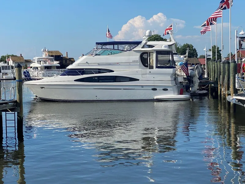 The Image of 2001 Carver 466 Motor Yacht docked at marina with flags and calm water. - 0