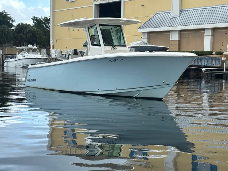 Slide: The Image of 2023 Sailfish 272 CC boat docked in calm waters near a marina. - 2