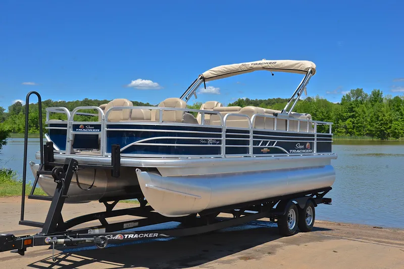 Slide: The Image of 2023 Sun Tracker Fishin Barge 20 DLX pontoon boat on trailer by a lake. - 10