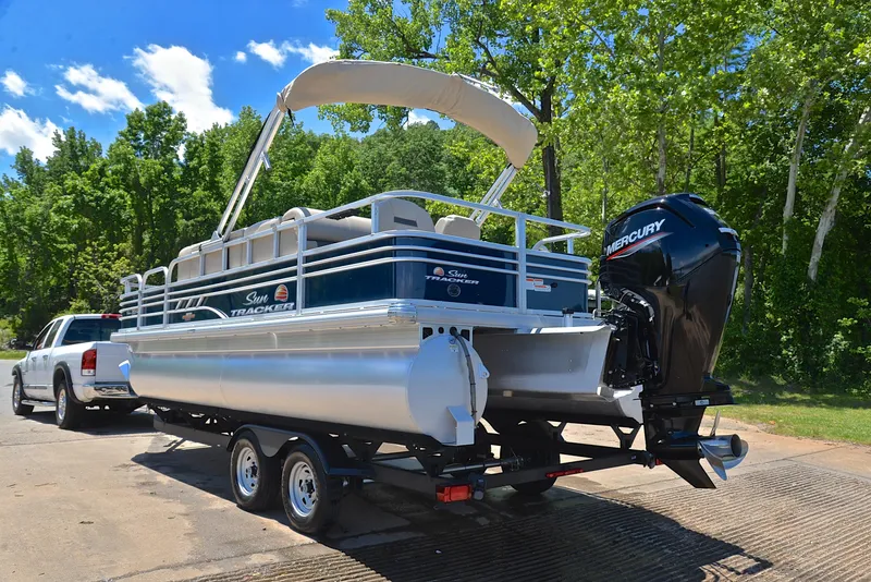 Slide: The Image of 2023 Sun Tracker Fishin Barge 20 DLX pontoon boat on trailer, parked near trees. - 12