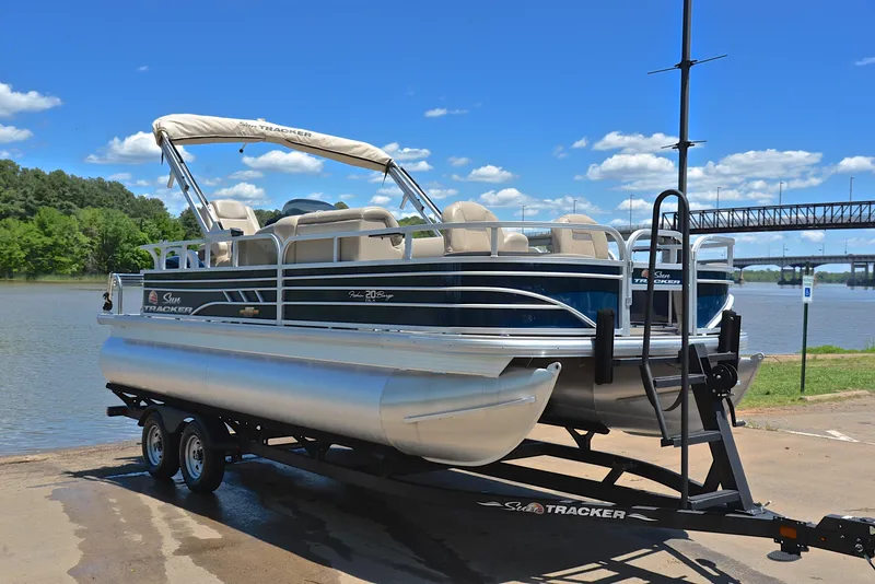 Slide: The Image of 2023 Sun Tracker Fishin Barge 20 DLX pontoon boat on trailer by a river. - 16