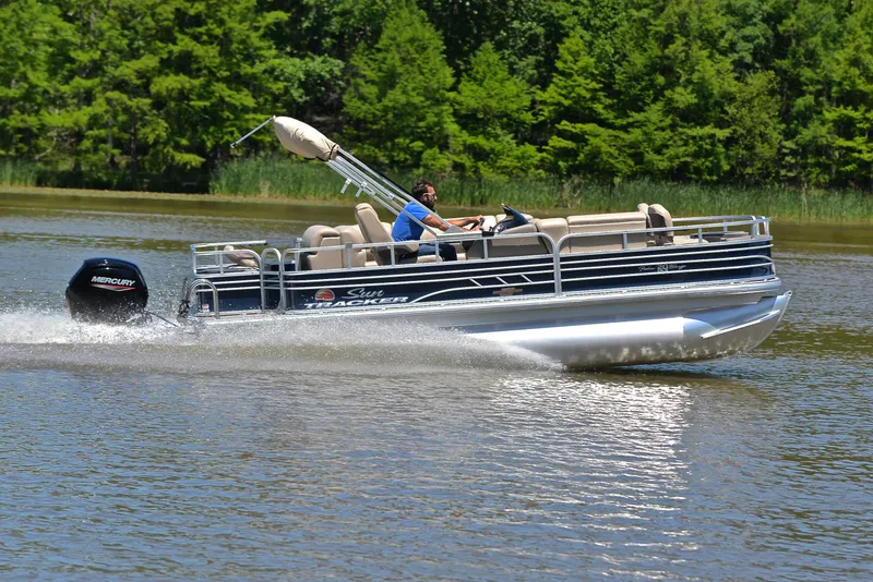 Slide: The Image of 2023 Sun Tracker Fishin Barge 20 DLX cruising on a lake with lush green trees. - 3