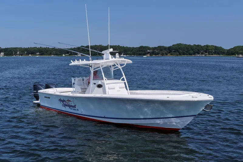 Slide: The Image of 2013 Regulator 34 Center Console boat on calm water, with scenic shoreline background. - 14