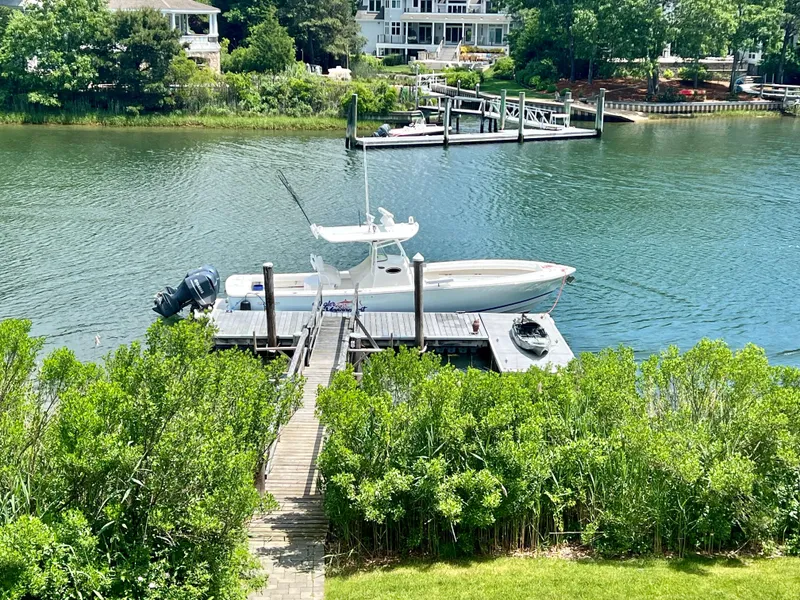 Slide: The Image of 2013 Regulator 34 Center Console boat docked on a serene river with lush greenery. - 16