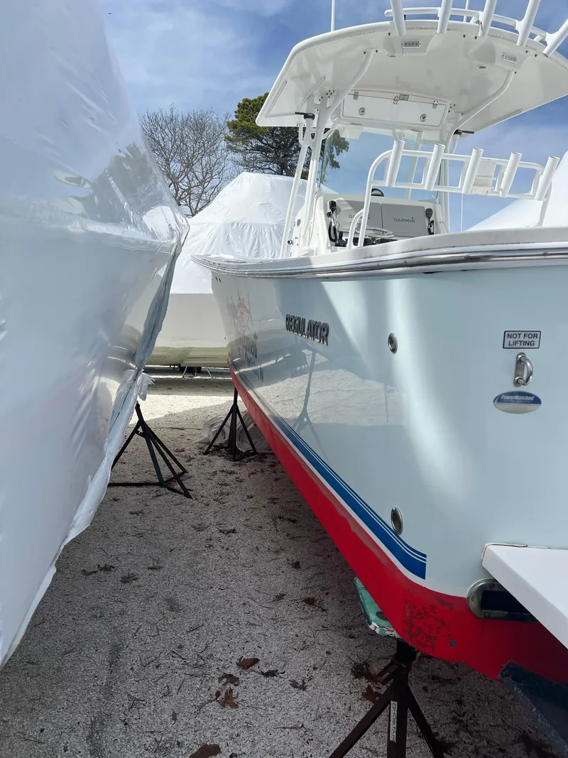 Slide: The Image of 2013 Regulator 34 Center Console boat on stands, partially covered, outdoors. - 18