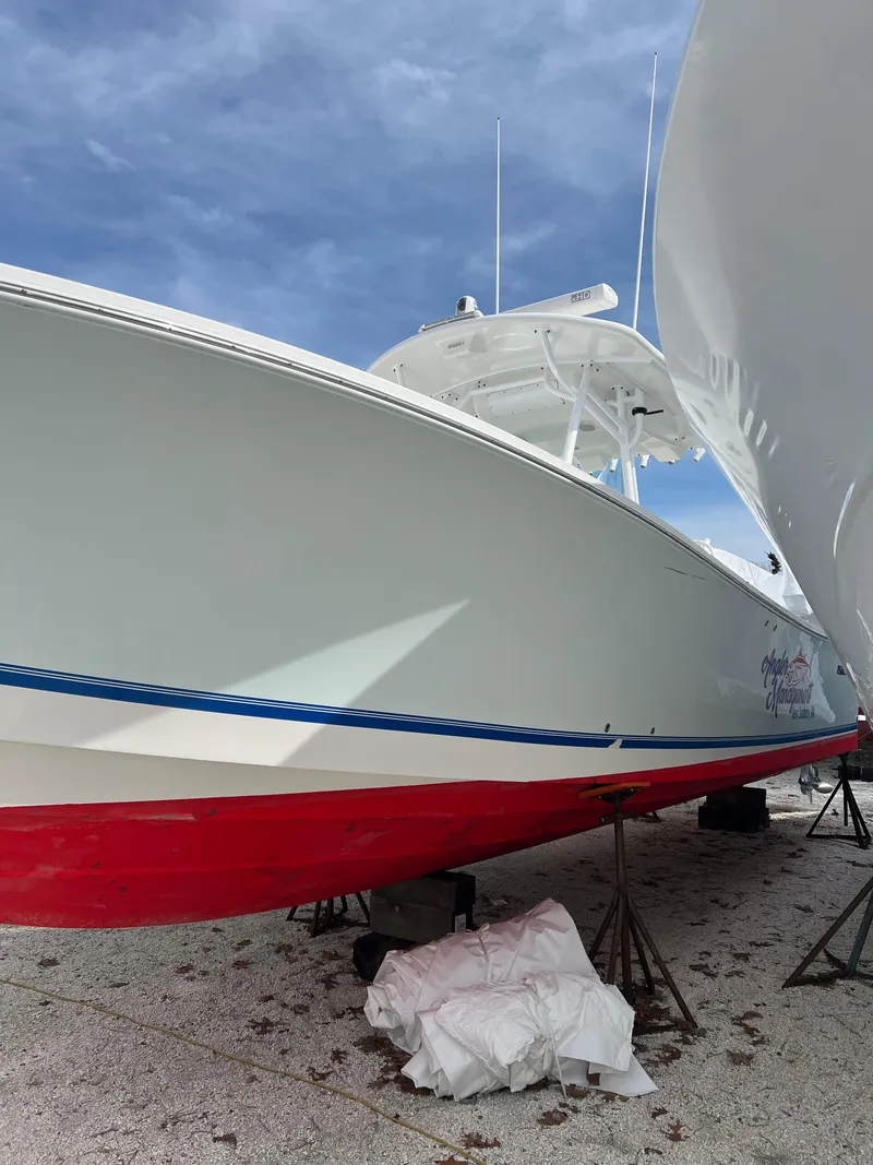 Slide: The Image of 2013 Regulator 34 Center Console boat with red hull, docked on land. - 19