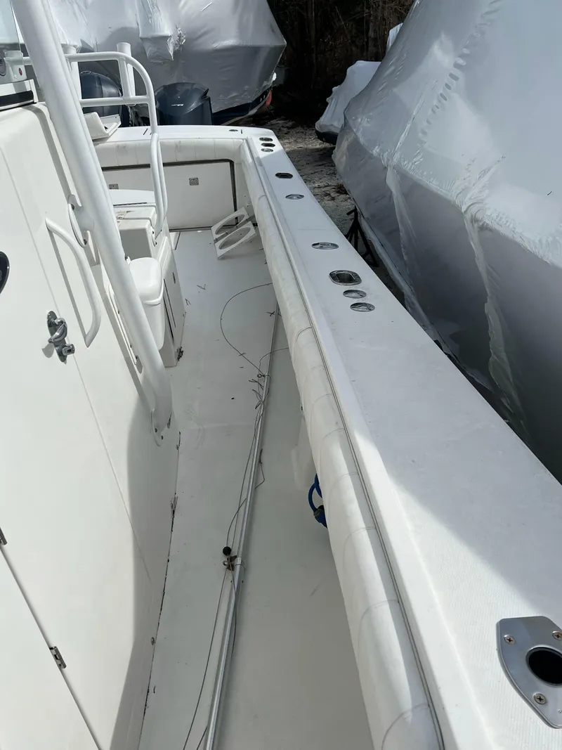 Slide: The Image of 2013 Regulator 34 Center Console boat, white deck, side view, docked, covered boats in background. - 29