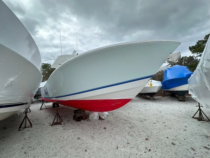 Slide: The Image of 2013 Regulator 34 Center Console boat with red hull, stored outdoors. - 31