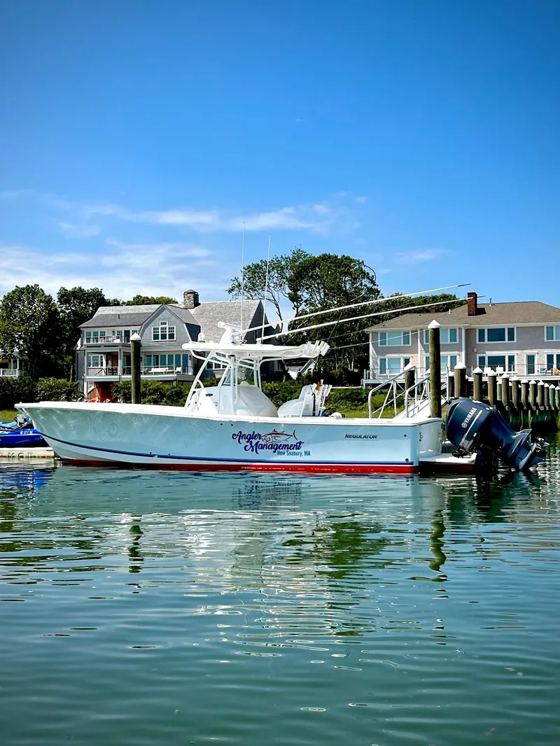 Slide: The Image of 2013 Regulator 34 Center Console boat docked by waterfront homes under clear blue sky. - 35