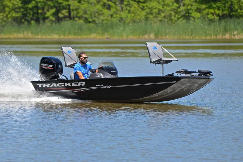 The Image of 2023 Bass Tracker Pro 170 boat cruising on a lake with lush green background. - 1