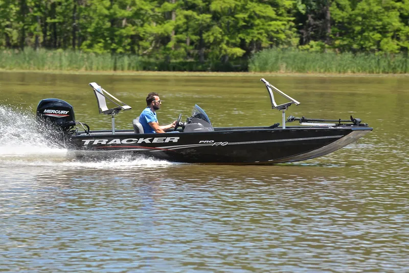 Slide: The Image of 2023 Bass Tracker Pro 170 boat speeding on a lake with lush green background. - 3