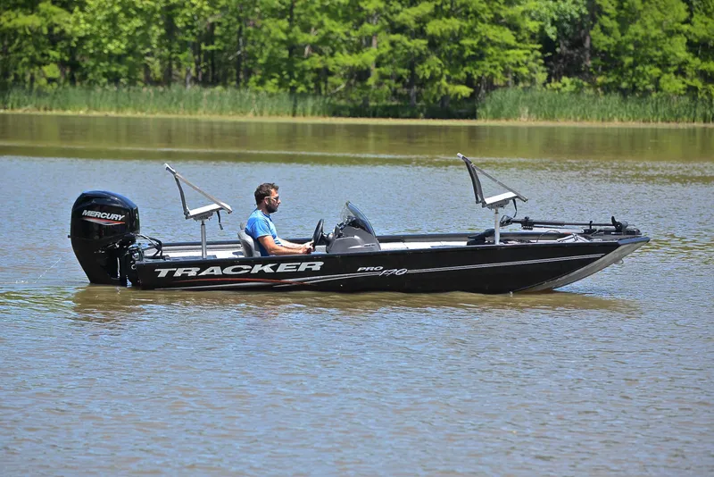 Slide: The Image of 2023 Bass Tracker Pro 170 boat on a calm lake with lush green background. - 7
