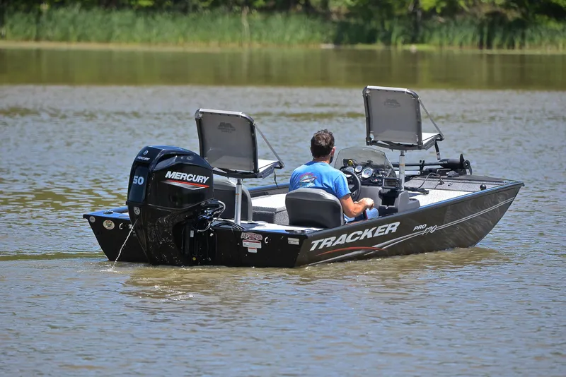 Slide: The Image of 2023 Bass Tracker Pro 170 boat on a calm lake with a Mercury engine. - 8