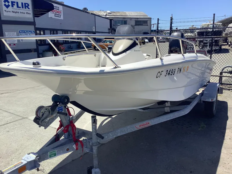 Slide: The Image of 2016 Boston Whaler 150 Super Sport boat on trailer in industrial setting. - 2