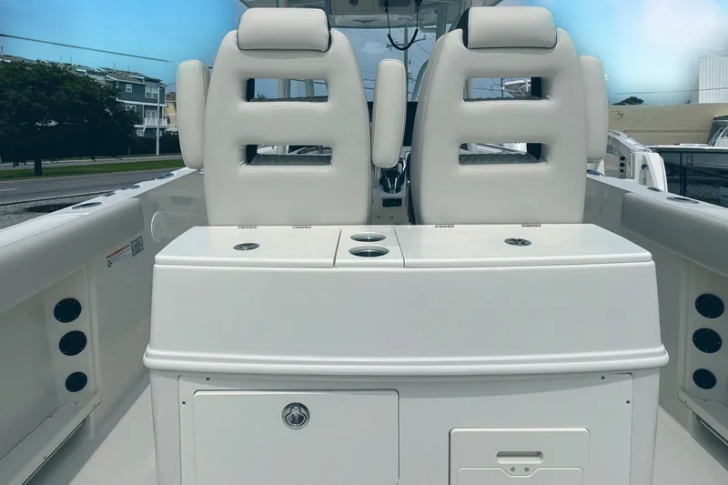 Slide: The Image of 2024 Sailfish 290 CC boat interior with dual white cushioned seats and storage compartments. - 10