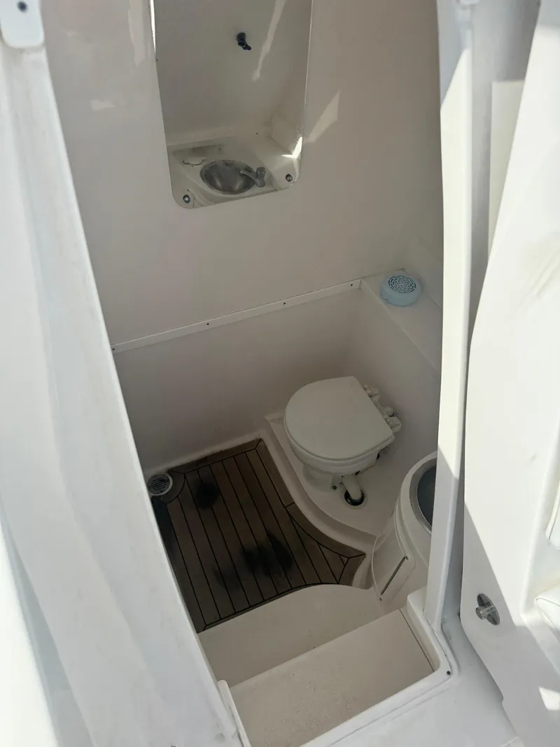 Slide: The Image of 2016 Intrepid 375 CC boat bathroom with toilet and sink, featuring wooden flooring. - 32