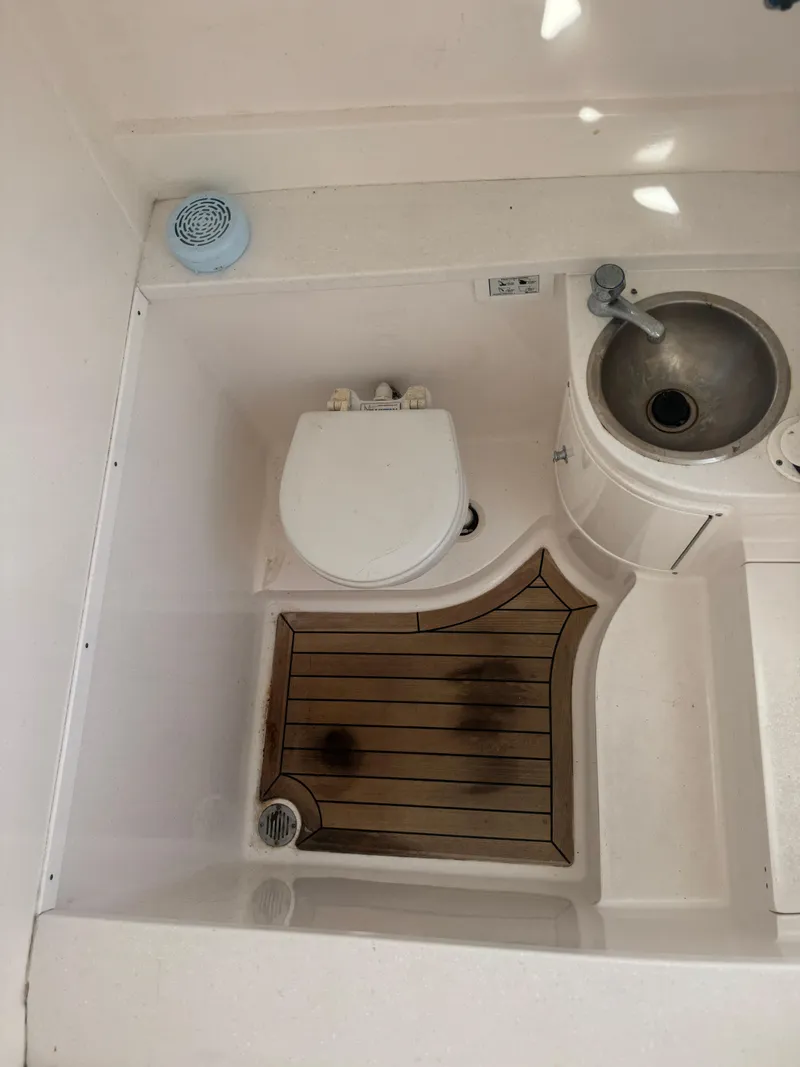 Slide: The Image of 2016 Intrepid 375 CC boat bathroom with toilet, sink, and wooden floor mat. - 33