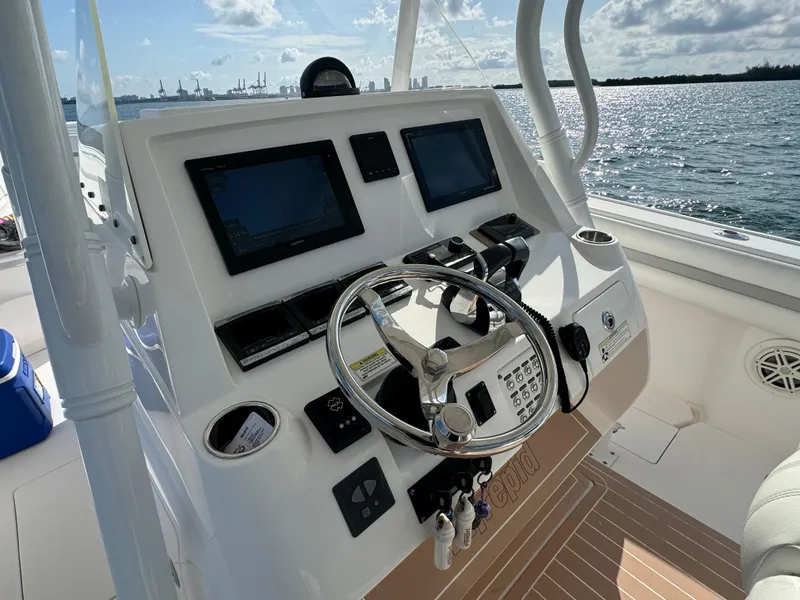 Slide: The Image of 2016 Intrepid 375 CC boat dashboard with steering wheel and navigation screens, on open water. - 8