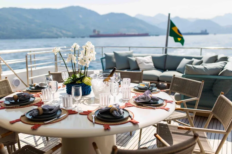 Slide: The Image of Luxurious Inace Explora 90 yacht deck with elegant dining setup, ocean view, and Brazilian flag. - 11