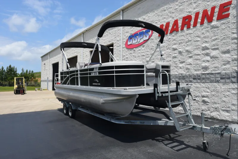 Slide: The Image of 2022 Bennington SX 23 Stern Lounge pontoon boat on trailer outside marine store. - 2