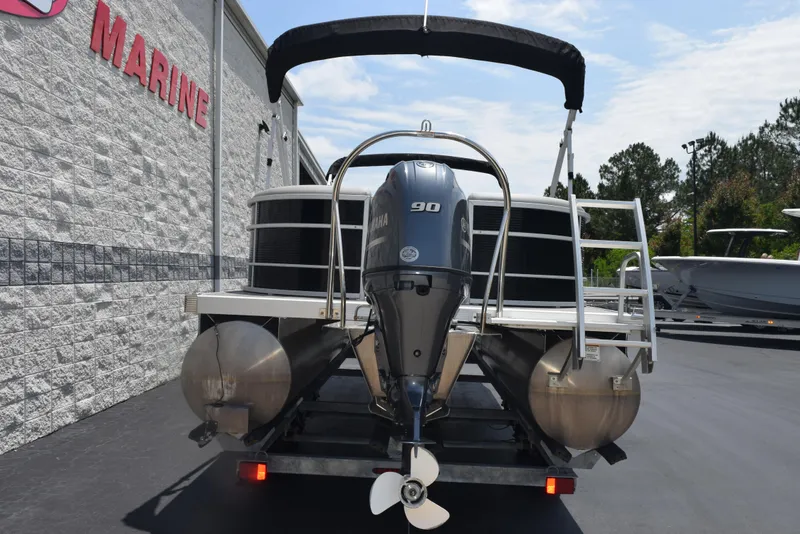 Slide: The Image of 2022 Bennington SX 23 Stern Lounge pontoon boat with outboard motor, parked at a marine facility. - 5