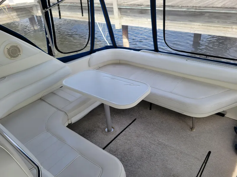 Slide: The Image of 1995 Sea Ray 370 Sundancer interior with white seating and table, dockside view. - 11