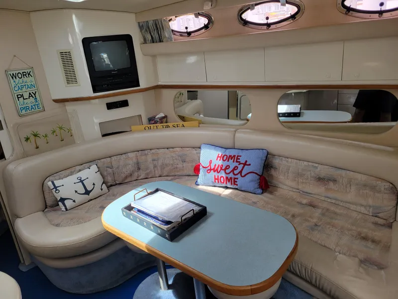 Slide: The Image of 1995 Sea Ray 370 Sundancer interior with cozy seating, nautical decor, and a small TV. - 17
