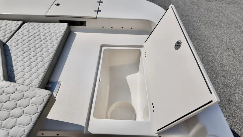Slide: The Image of 2025 Carolina Skiff 21 LS Stealth Edition storage compartment with open lid and cushioned seating. - 13