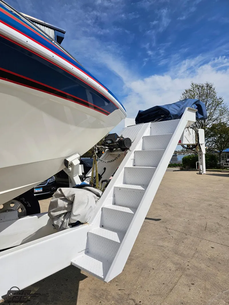 Slide: The Image of 2002 Black Thunder 460 SC boat with white stairs, parked outdoors under a blue sky. - 12