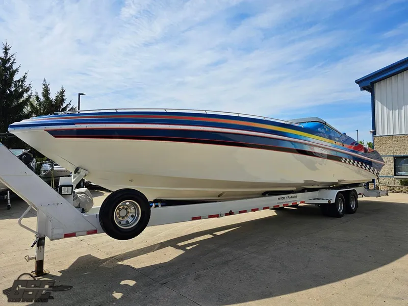 Slide: The Image of 2002 Black Thunder 460 SC powerboat on trailer, vibrant stripes, parked outdoors. - 14