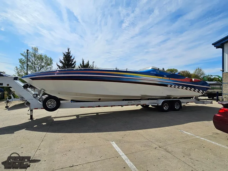Slide: The Image of 2002 Black Thunder 460 SC speedboat on trailer, vibrant stripes, parked outdoors under blue sky. - 15