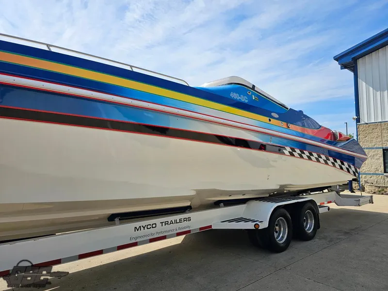 Slide: The Image of 2002 Black Thunder 460 SC boat on Myco trailer, vibrant stripes, parked outdoors. - 17