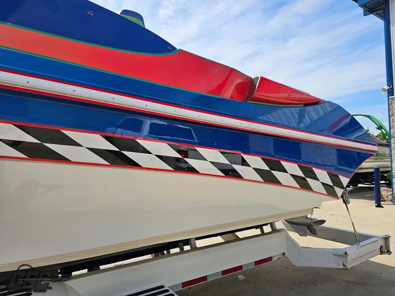 Slide: The Image of 2002 Black Thunder 460 SC boat with vibrant red, blue, and checkered design on a trailer. - 20