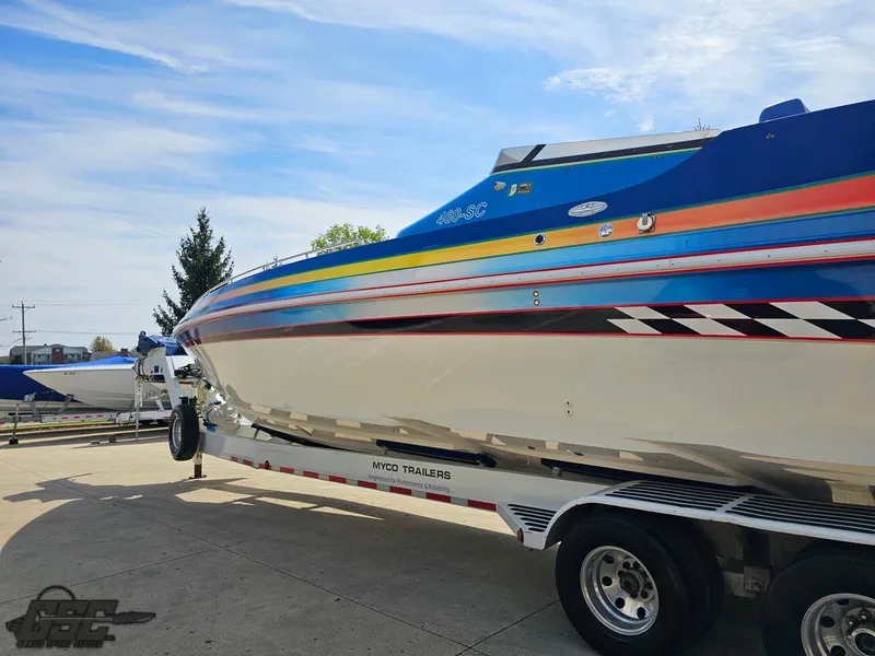 Slide: The Image of 2002 Black Thunder 460 SC boat on trailer, vibrant stripes, parked outdoors. - 22