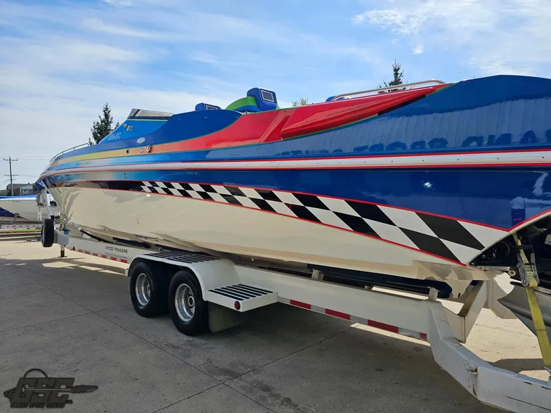 Slide: The Image of 2002 Black Thunder 460 SC speedboat on trailer, vibrant colors, checkered design, sunny day. - 24