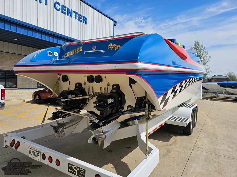 Slide: The Image of 2002 Black Thunder 460 SC powerboat on trailer, vibrant blue and red design, parked outside a center. - 31