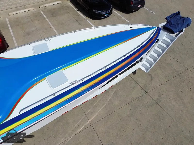 Slide: The Image of 2002 Black Thunder 460 SC boat with vibrant blue and yellow design, parked on concrete. - 35