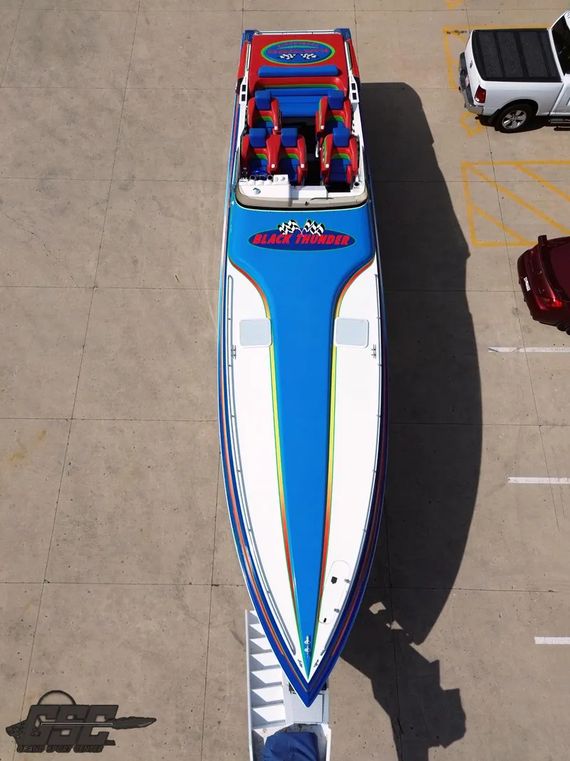 Slide: The Image of 2002 Black Thunder 460 SC boat, vibrant blue and red design, parked on concrete surface. - 36