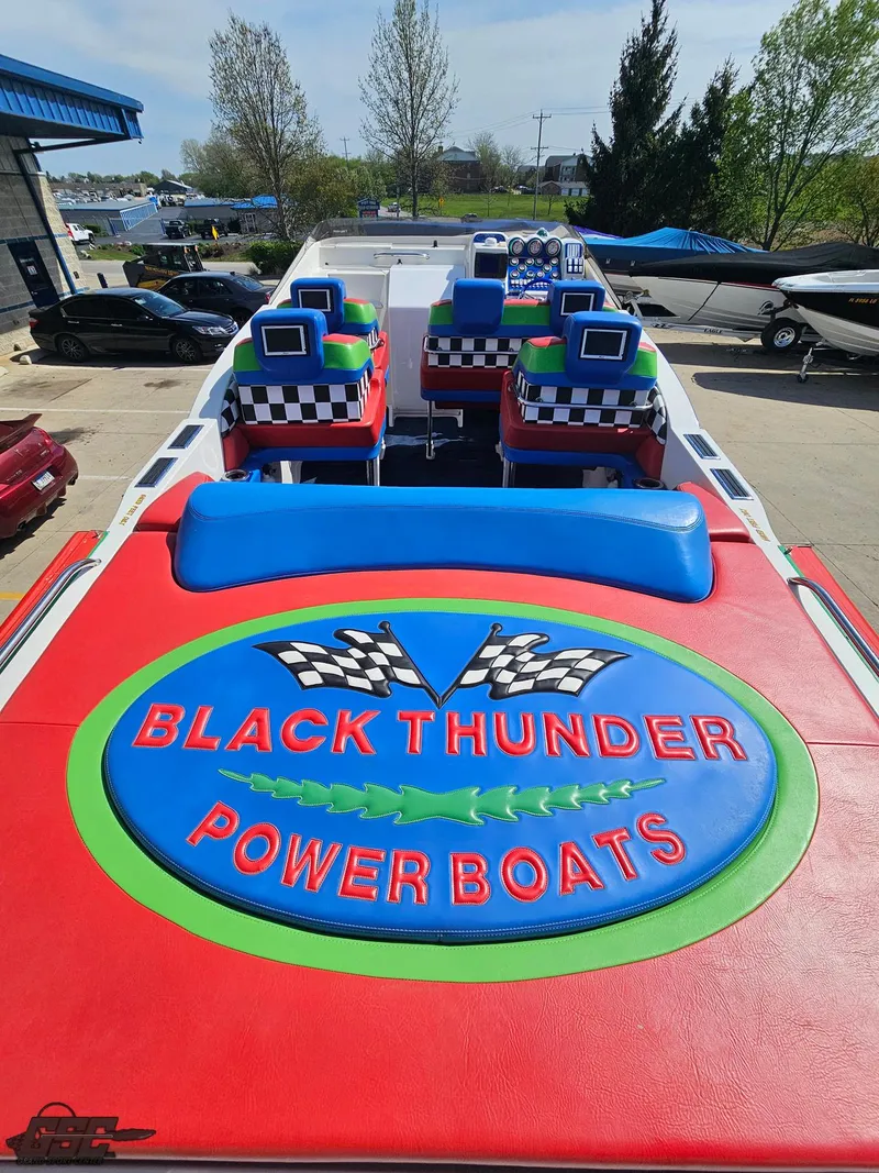 Slide: The Image of 2002 Black Thunder 460 SC powerboat with colorful seating and logo, docked outdoors. - 44