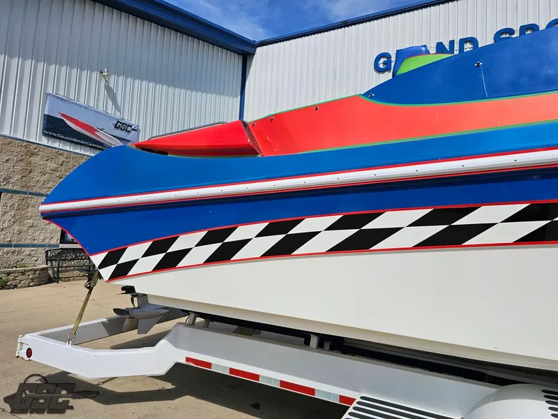 Slide: The Image of 2002 Black Thunder 460 SC boat with vibrant colors on a trailer outside a building. - 7