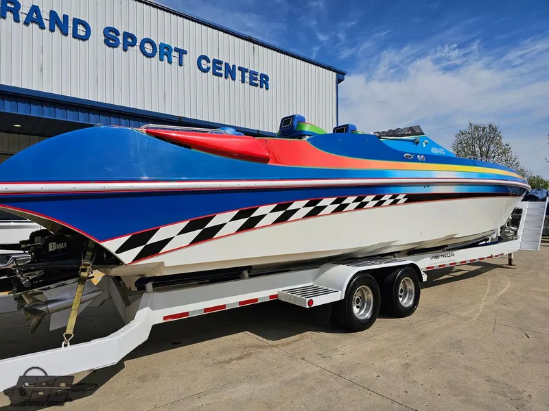 Slide: The Image of 2002 Black Thunder 460 SC boat with vibrant colors on a trailer at a sport center. - 8