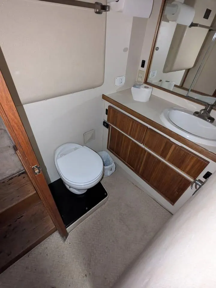 Slide: The Image of 1988 Bertram 37 Convertible yacht bathroom with toilet, sink, and wooden cabinetry. - 19