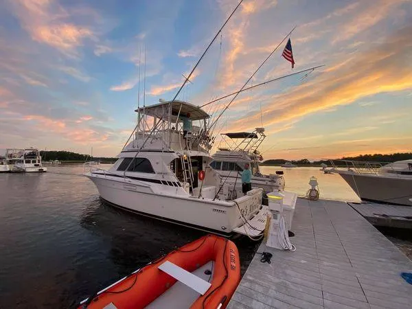 Slide: The Image of 1988 Bertram 37 Convertible yacht docked at sunset with vibrant sky and American flag. - 3